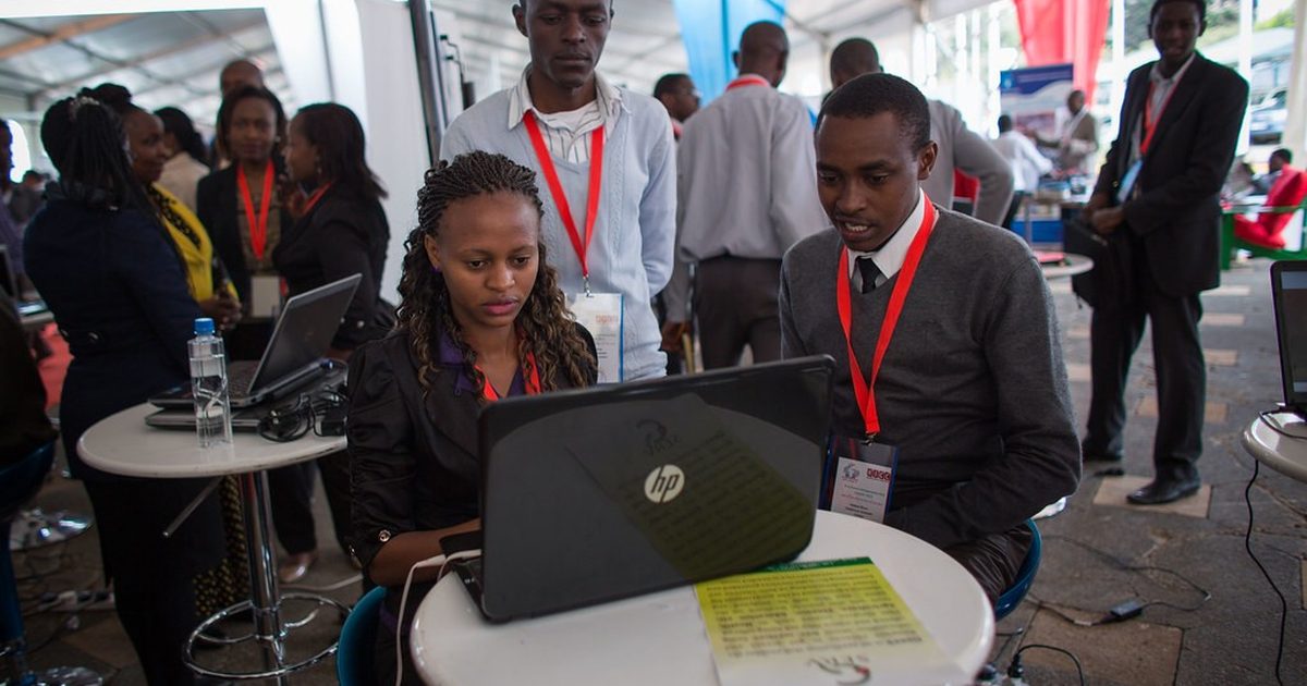 Young Kenyan entrepreneurs gathered around a laptop at an innovation event