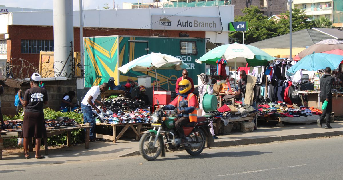 Boda boda rider passing roadside traders on a Nairobi street