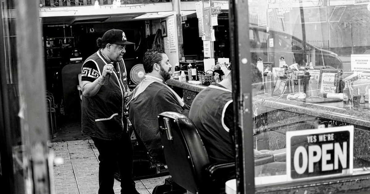 Barber cutting a client's hair in a busy barbershop